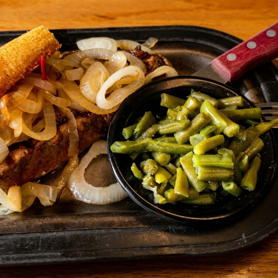Steak with caramelized onions, a fried cheese stick, and a side of green beans on a metal plate.
